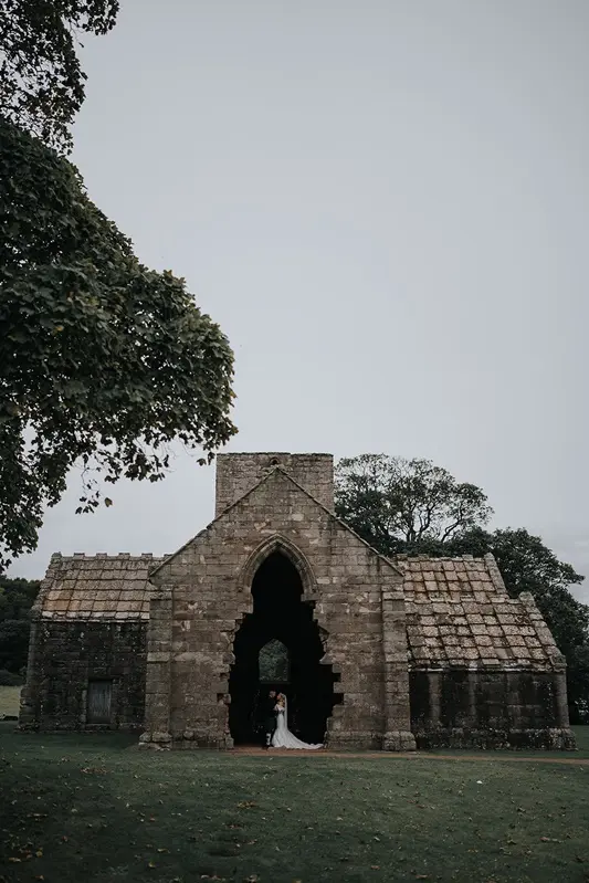 Wedding couple framed by historic Scottish ruins